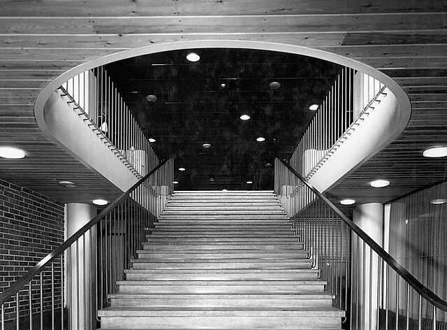 Staircase with black railings leading to a dark upper floor with circular lights.