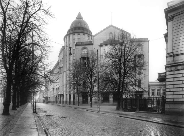 Cobblestone street with multiple storey building with a cupola.