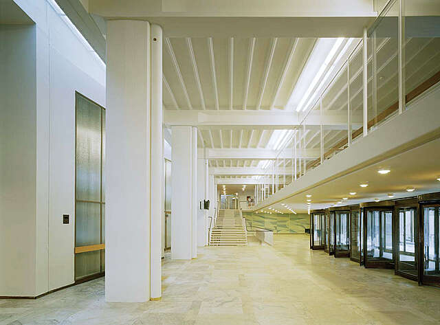 White entrance lobby with marble floors and metal circular moving doors.