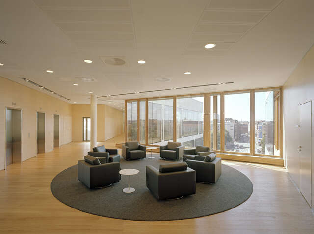 Seating area in front of elevators, the wooden surfaces of the room give the space warm feeling.