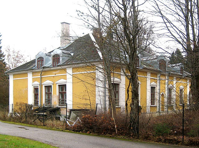 Old yellow house with white decorative elements and grid windows, the paint has chipped in several points.