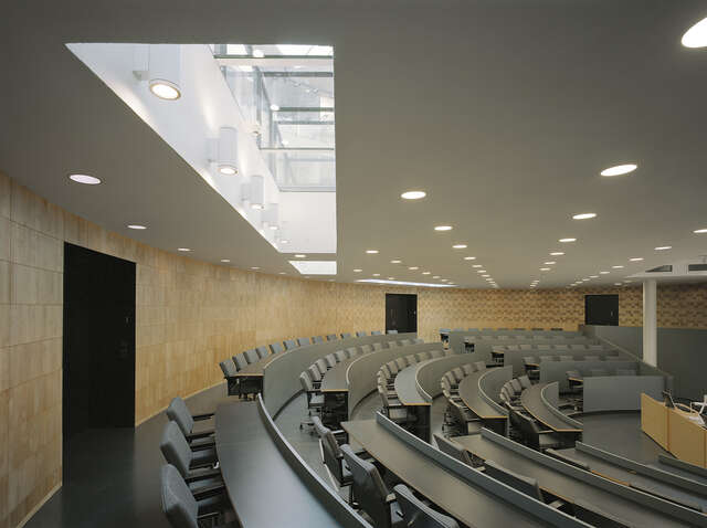 Auditorium with chairs and tables positioned in a semi circle.