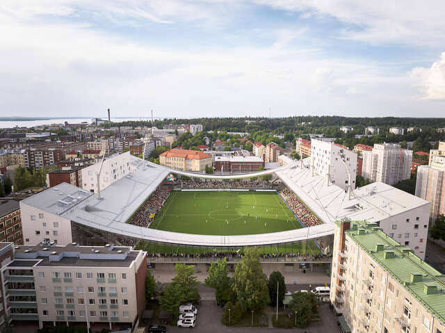 Aerial photograph of a hybrid stadium dedicated to football that also houses shops, offices, and apartments.