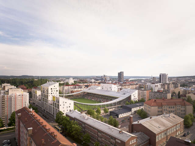 Aerial view of a football stadium with several older buildings seen nearby it.