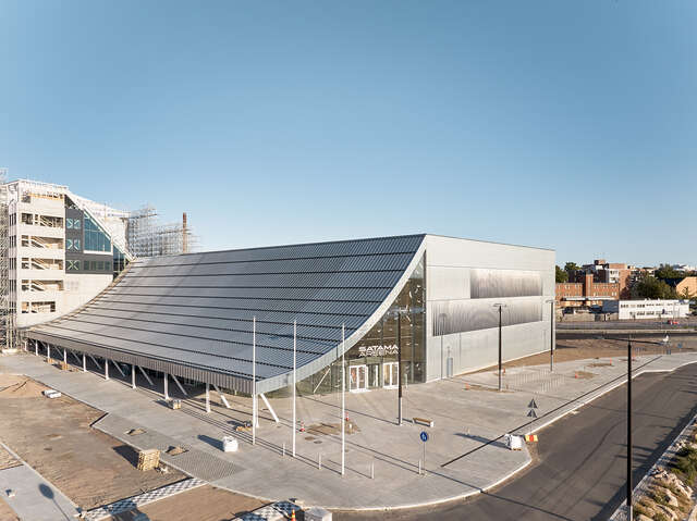 Zinc-covered box-shaped building with a curved sloping ceiling in the front facade