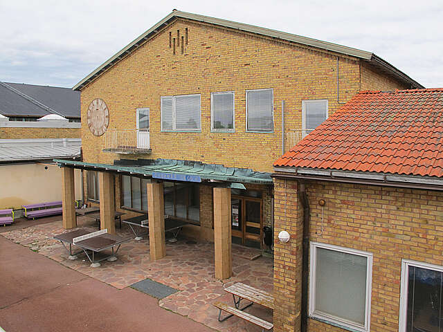 Yellow-brick facade with pingpong tables in the yard.