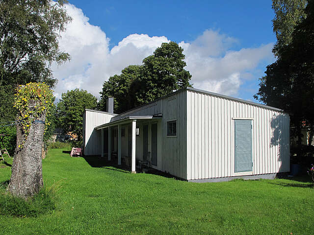 White wooden shed with light blue doors in a yard.