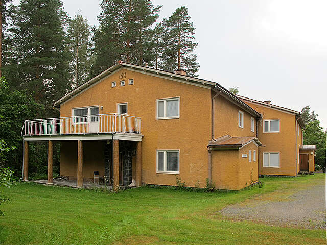 Yellow two story side building with trees to the left.