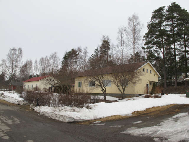 Long yellow plastered house with brown window frames on a grey winter day.