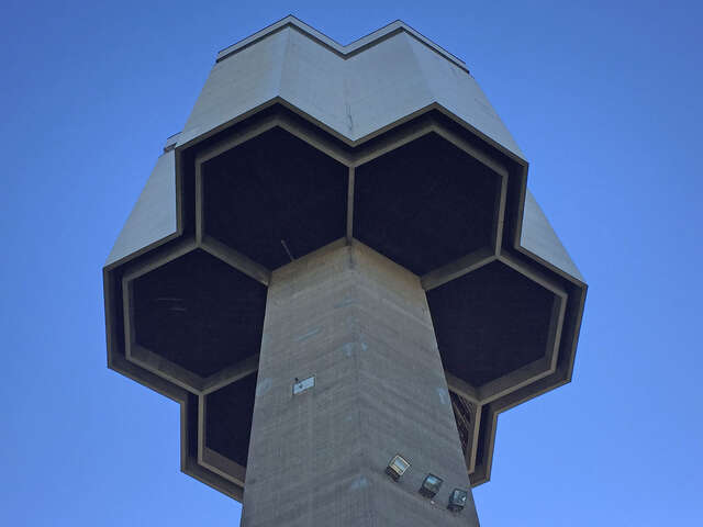 Water tower in brutalist style building has a honeycomb-shaped hexagon distributor reservoir.