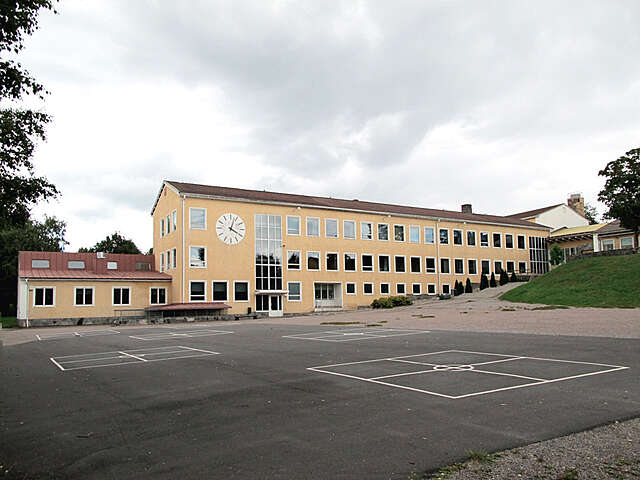School yard with painted stares on the concrete, the yellow school building is at the back.