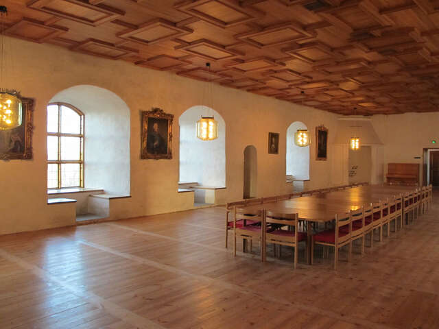 Restaurated hall with very old grid windows, a new floor and ceiling and a Lon dining table with matching chairs.