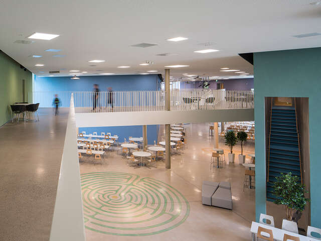 School hallway with colored walls, the school canteen is visible from the second floor.