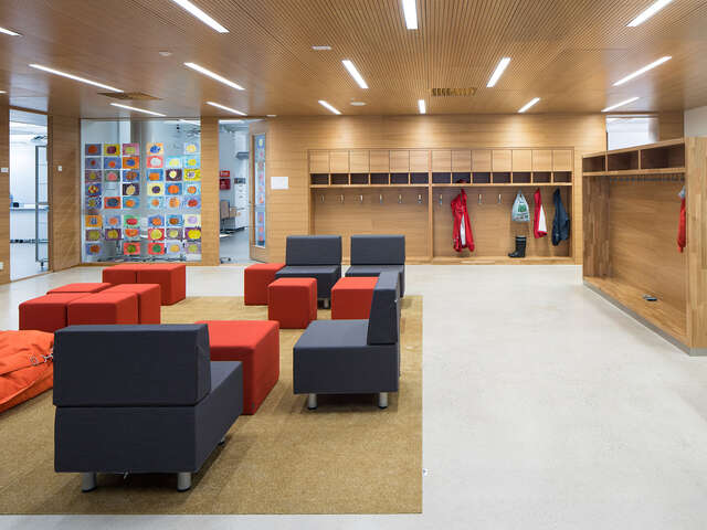 Seating area with grey and orange armchairs and stools next to the wardrobe.