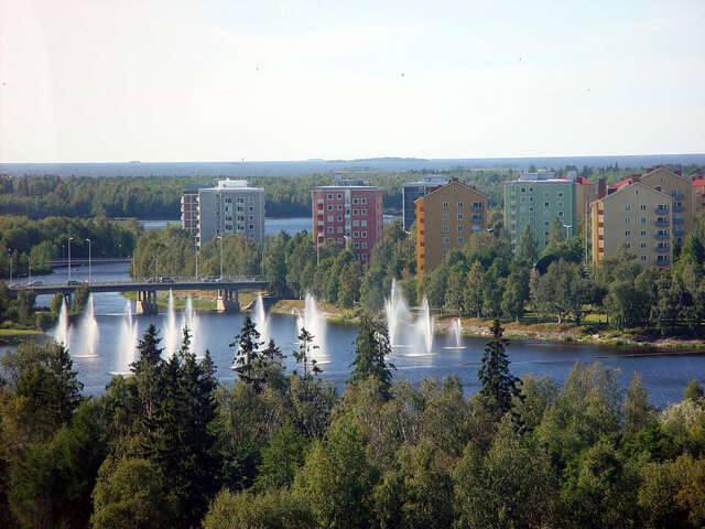 View from far away towards a water mirror with fountains and colourful point blocks.