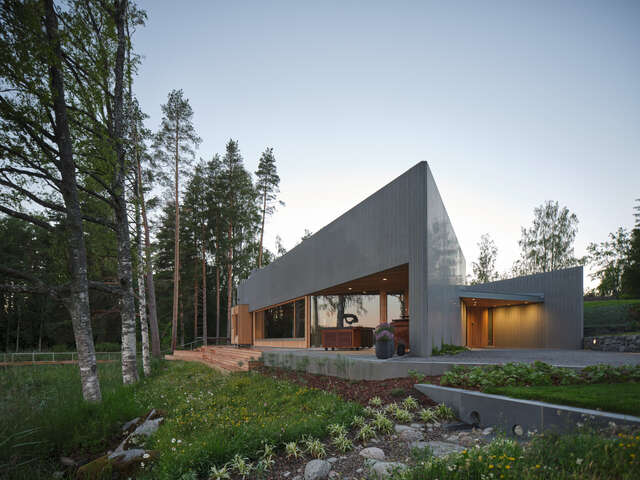 Gray sauna building with warm lights and wooden details.