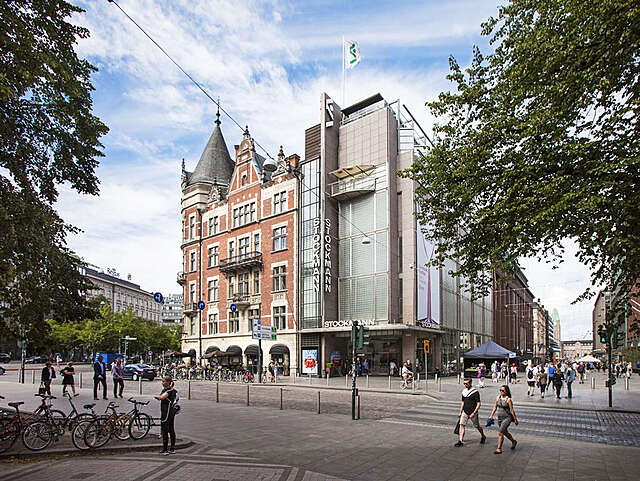 The grey stockman building contrasts to the red tile jugged style building next to it.