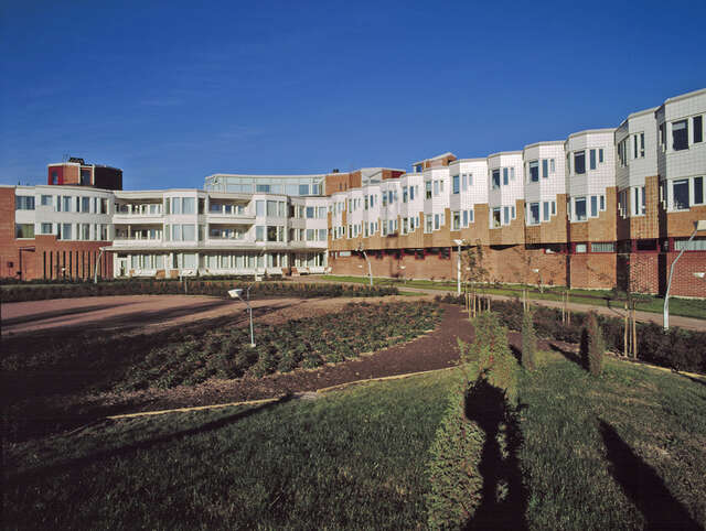 Stepped building facade of red bricks, white and brown tiles.