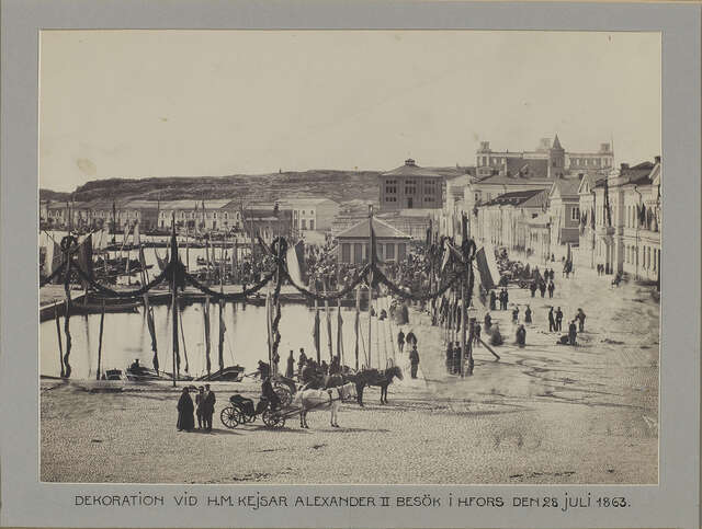 Old black and white picture of the harbor with people swarming a building.