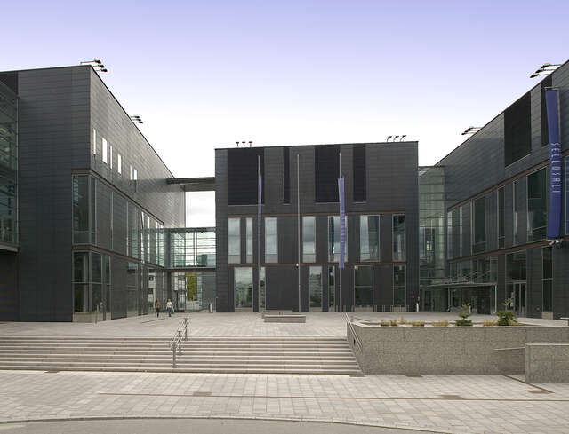 Grey building facade with several wings.