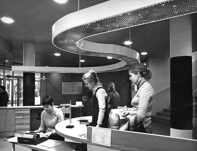 Women in front o fate lending desk in an black and white picture.