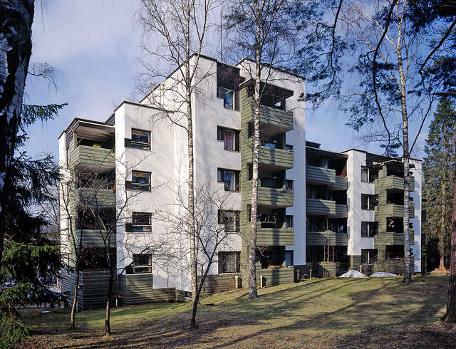 White and green building facade with protruding balconies.