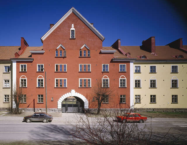 Apartment building on the opposite side of the street, two cars, blue sky