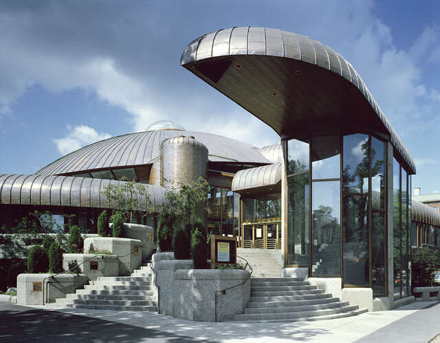 Facade with metal, glass and stone elements with curved lines.