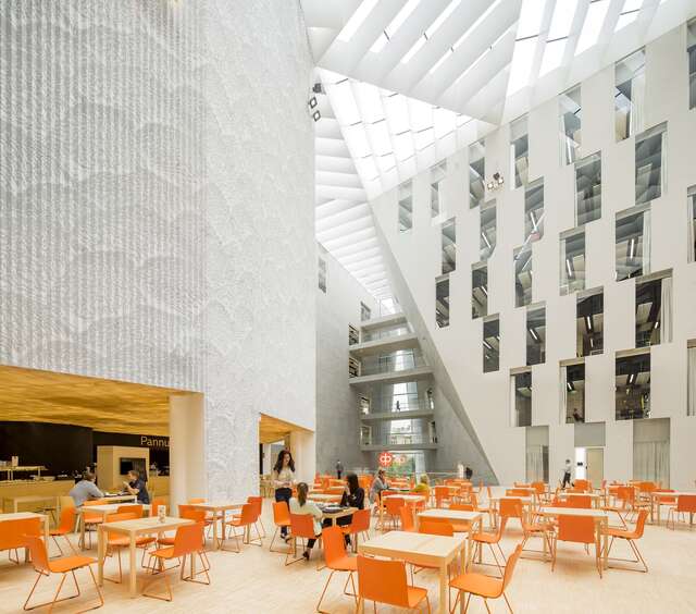 Cafeteria tables and orange chairs in a modern office environment.