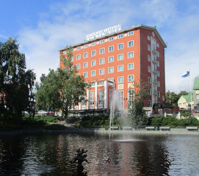 A pond with a fountain, a hotel behind it
