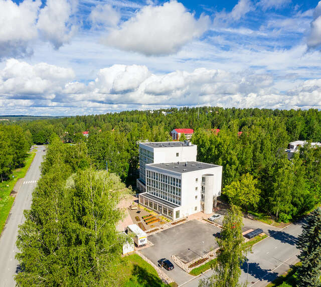 A large white building in the middle of trees