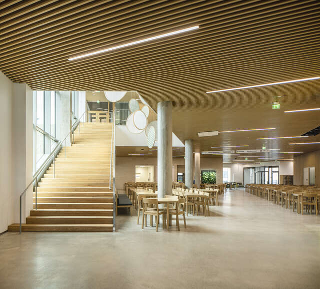 Lobby of a school building with a large staircase and set of tables and chairs.