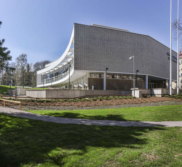 White tile facade with a glass wall at the back of the building.