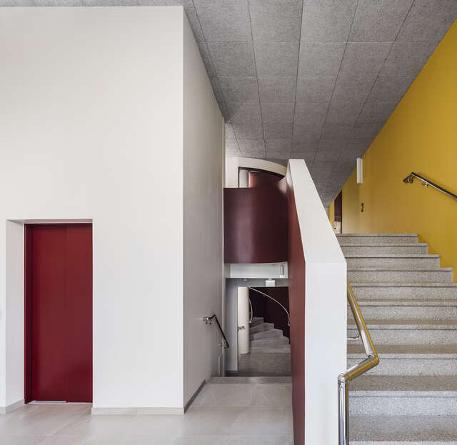 A stairwell of an apartment building, with yellow walls and red doors