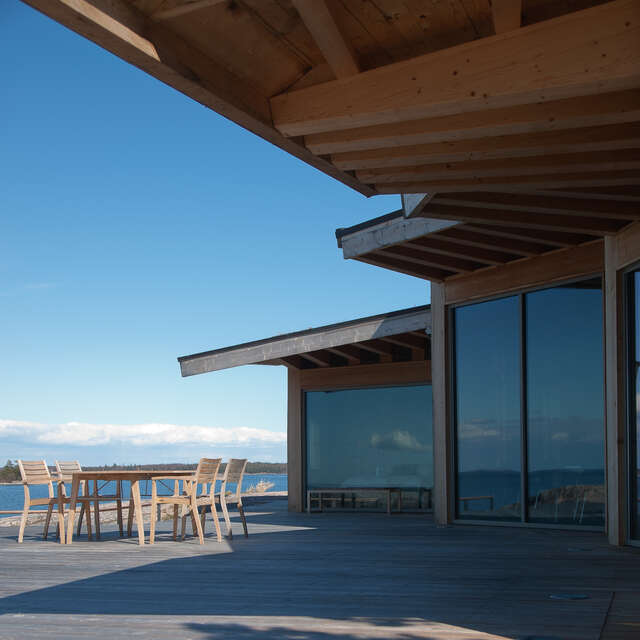 Terrace and dinette under a wooden canopy of the summer house with large glass windows