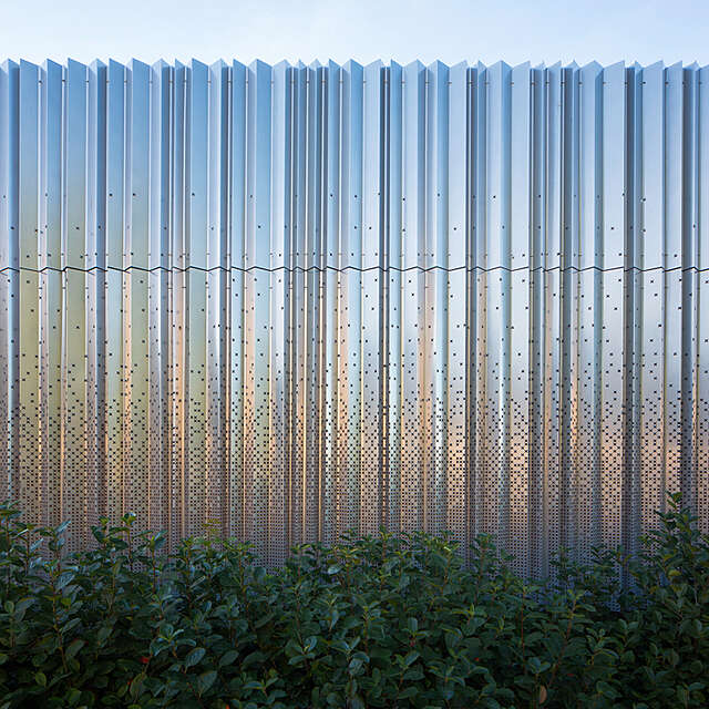 Metal wall with cross pattern that becomes more frequent at the bottom.