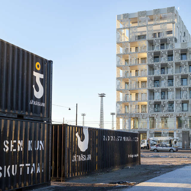 White apartment building exterior with metallic grid details in an almost checkered pattern.