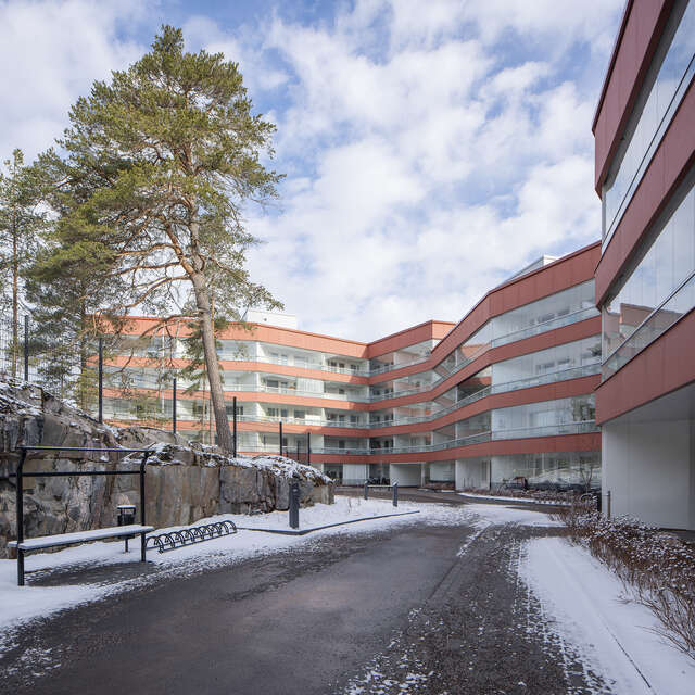 Apartment building with red metal and glass elements on a snowy day.