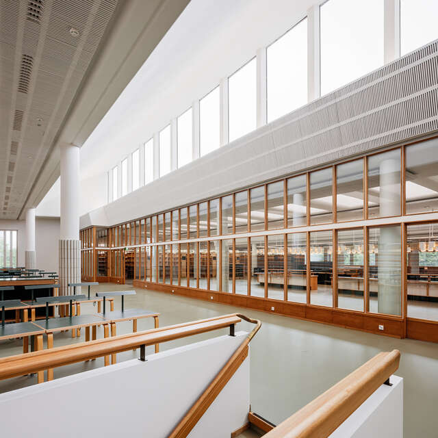 Hallway at the top of stairs with wooden and glass elements.