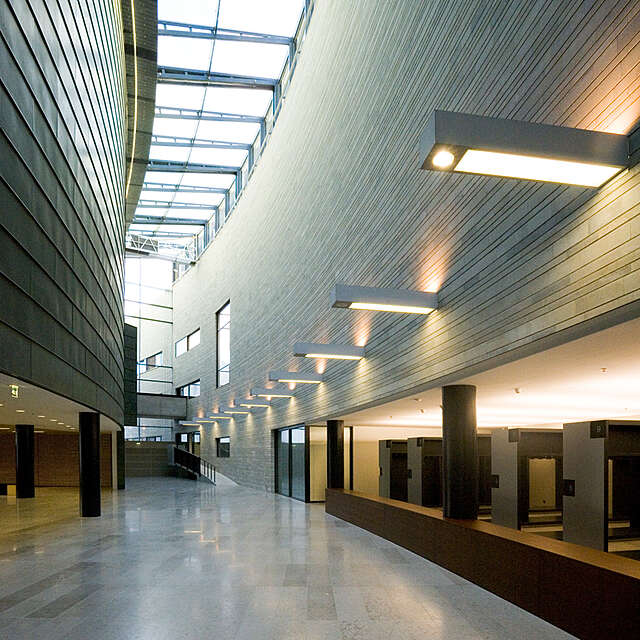 Entrance with a wardrobe, the walls are in curved lines and are covered in stone and metal.