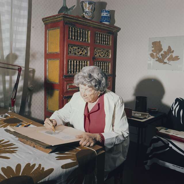 An elderly lady at a drawing desk