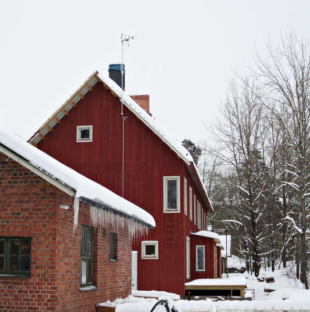 A brick sauna building in front of a wooden building.