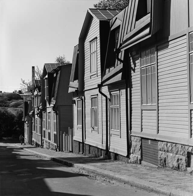 Row of wooden house on a sloped street in a black and white picture.