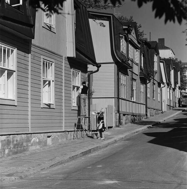 Row of wooden houses on a sloped street in a black and white picture.