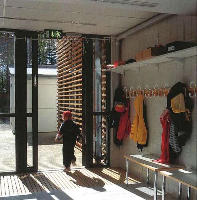 Hallway with coat racks. A child is exiting the the door.