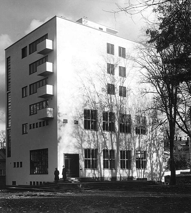 White rectangular building with wooden framed windows.
