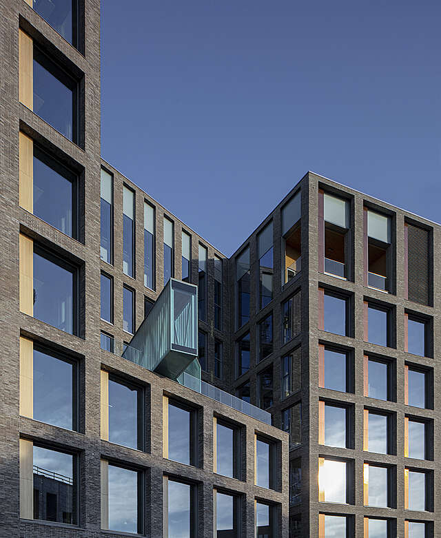 Brown brick facade, large square windows in a grid, some box-like pavilions on the roof