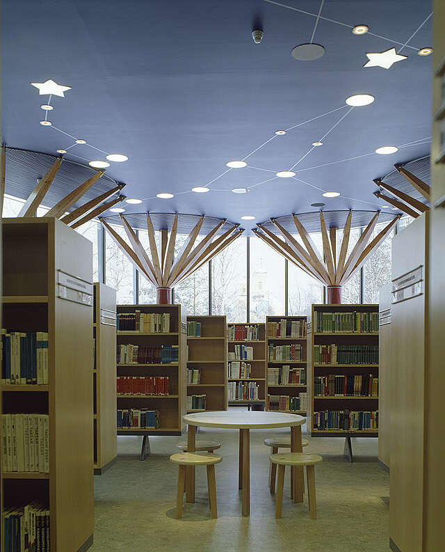 Circular table with chairs surrounded by bookshelves.