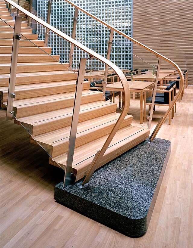 Black marble stepping stone that serves as the first step of wooden stairs.