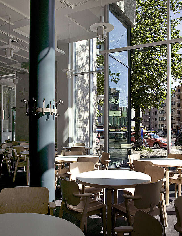 Café interior with round tables and a dark supporting column.